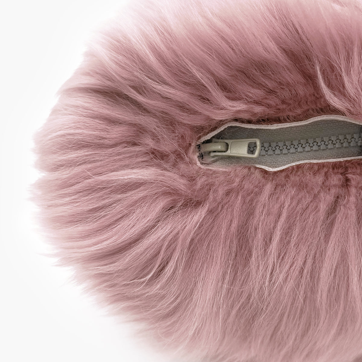 The Mood Charlie Sheepskin Double-sided Pillow in a pastel pink color, close-up view of zipper closure
