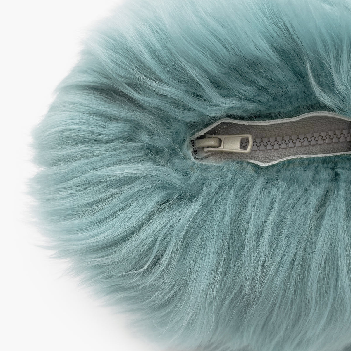 The Mood Charlie Sheepskin Double-sided Pillow in a pastel blue color, close-up view of zipper closure