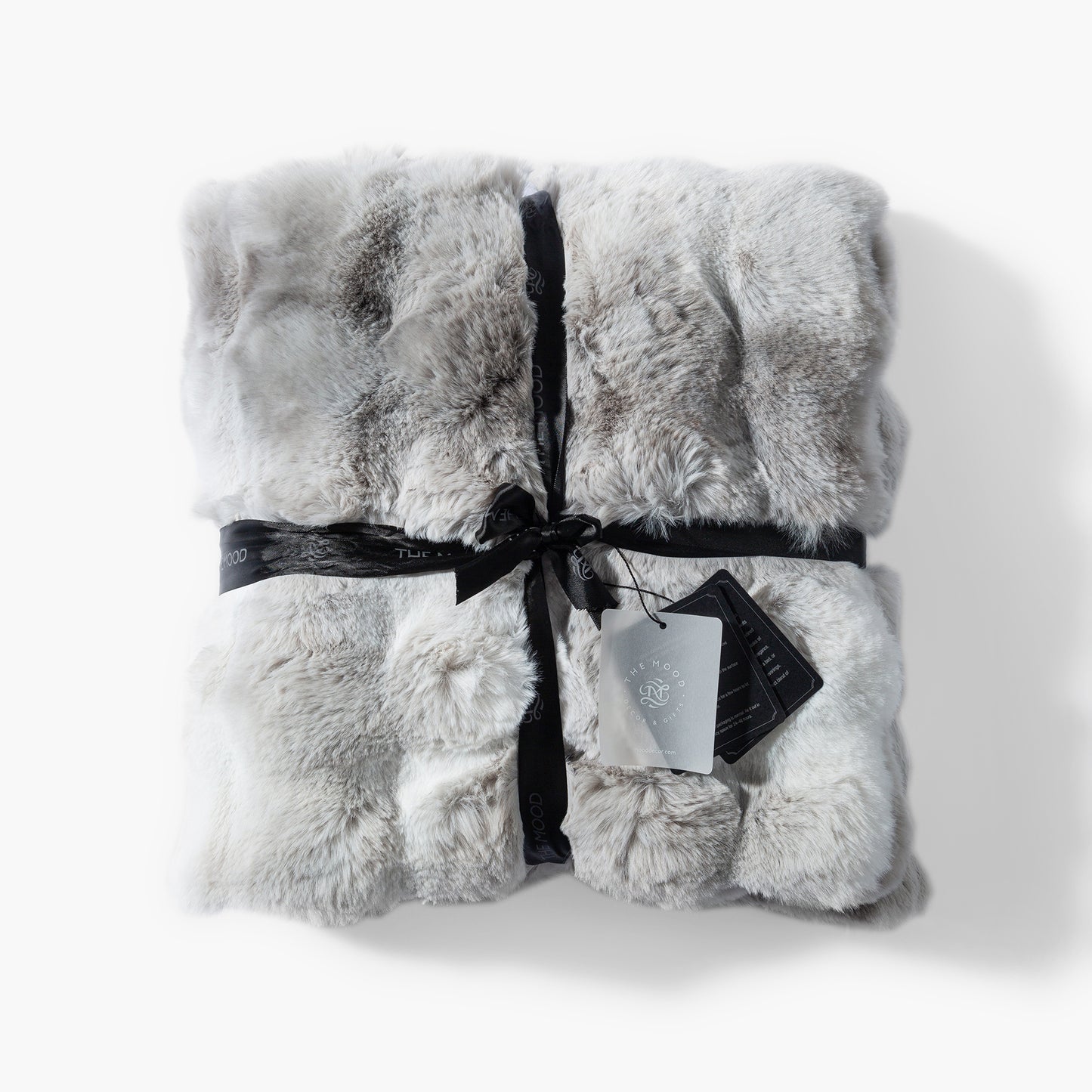 The Mood Cubby 2 faux fur throw in gray and white wrapped in a ribbon with product tags attached, ready for gifting