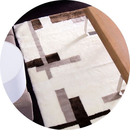 White geometric patterned area rug lying in front of a couch in a living room, representing the category of 'accent rugs'