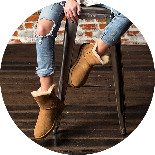 Woman wearing blue jeans and brown shearling short boots sitting on a gunmetal bar stool, representing the category of 'apparel and accessories'