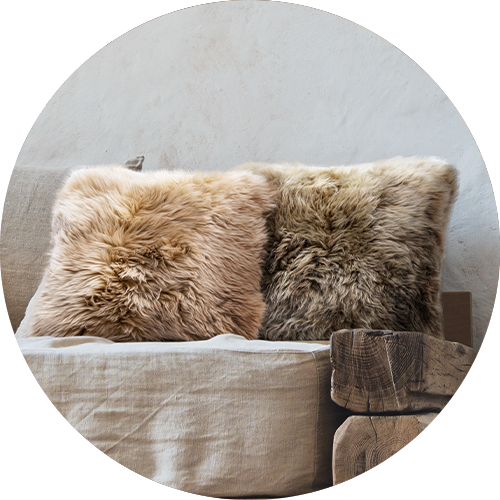 Two fluffy sheepskin pillows on a linen sofa, representing the category of 'decorative pillows'